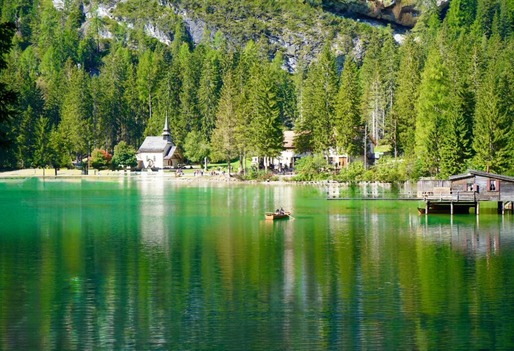 Tranquil alpine lake view with a chapel, forest, and reflections.